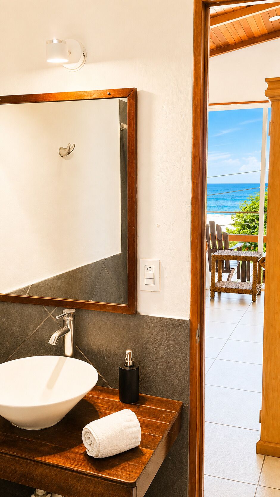 A bathroom with a large mirror, a white sink, a towel, and a bottle.