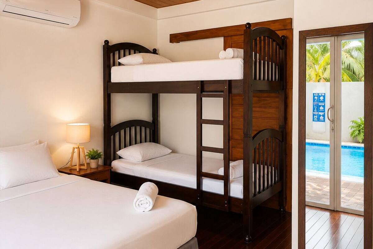 Une chambre avec un lit superposé, un lit simple, une lampe de chevet, une plante en pot et une vue sur une piscine.