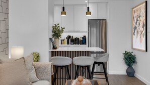 Eine moderne Küche mit integriertem Kühlschrank, zwei Pendelleuchten und einer Bar mit Sitzgelegenheiten.