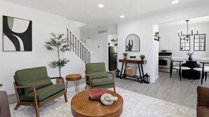 Una sala de estar moderna con un sofá, un sillón y una mesa de centro redonda de madera.