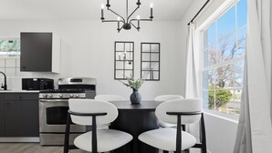 Una cocina moderna con una mesa redonda, sillas blancas y una lámpara de araña negra.