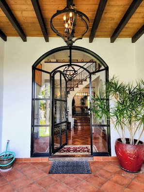 Una imponente entrada con puerta de vidrio, escalera y una planta grande en maceta.
