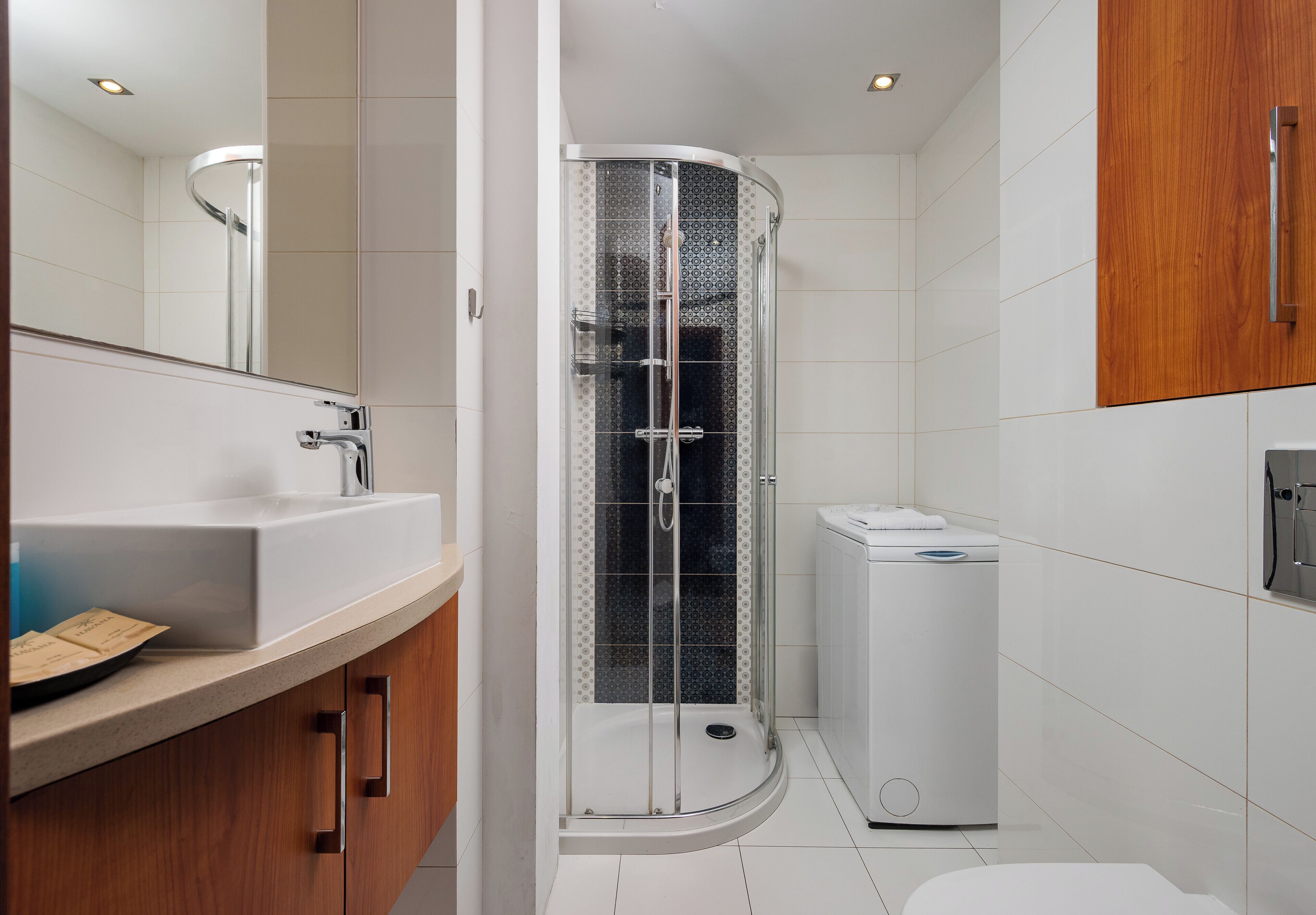 A modern bathroom with a glass-enclosed shower, a white sink, and a wooden vanity.