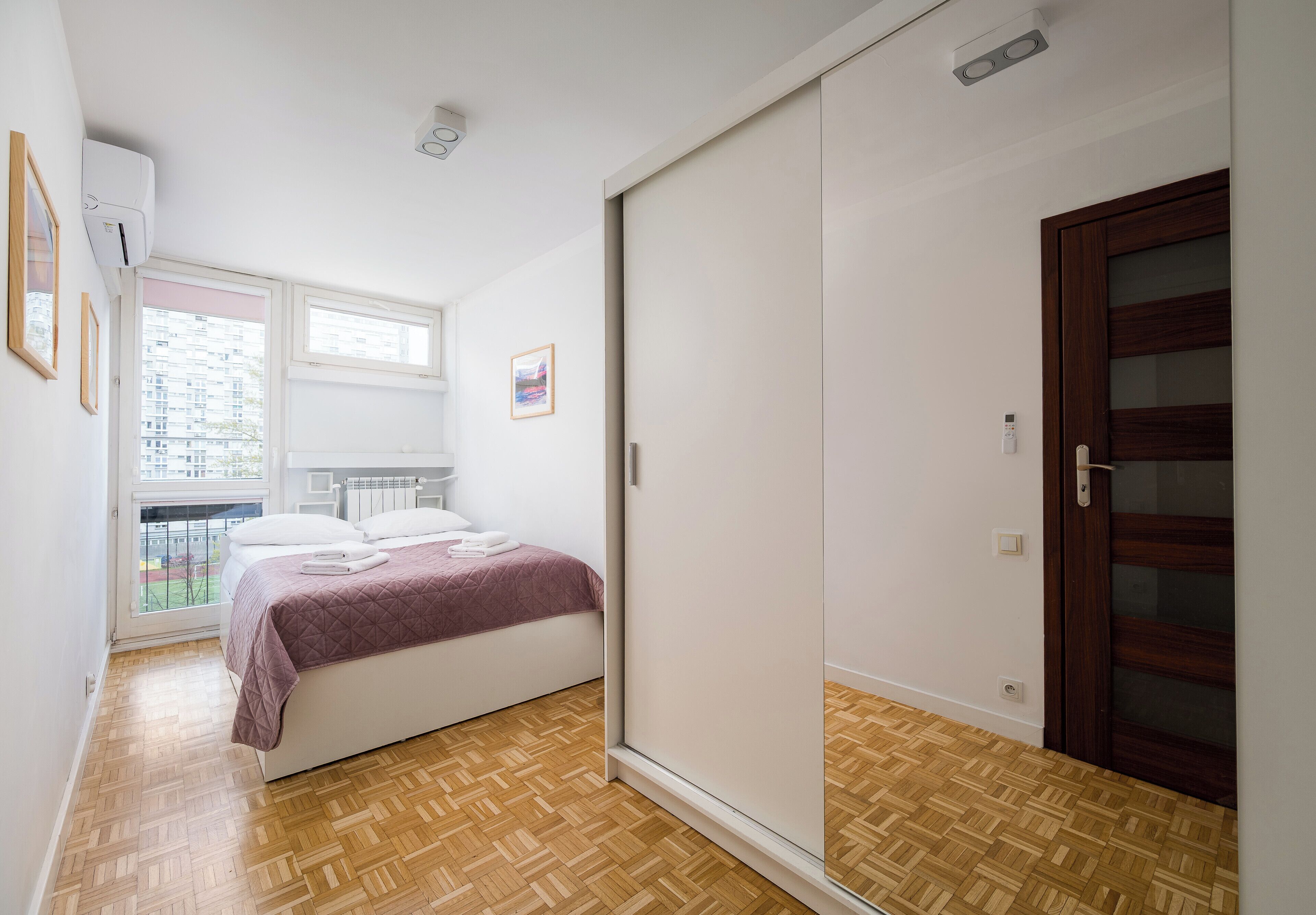A bedroom with a bed, a wardrobe, a window, and a door.