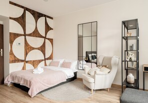 Een moderne slaapkamer met een bed, een stoel, een spiegel en een plank met decoratieve objecten.