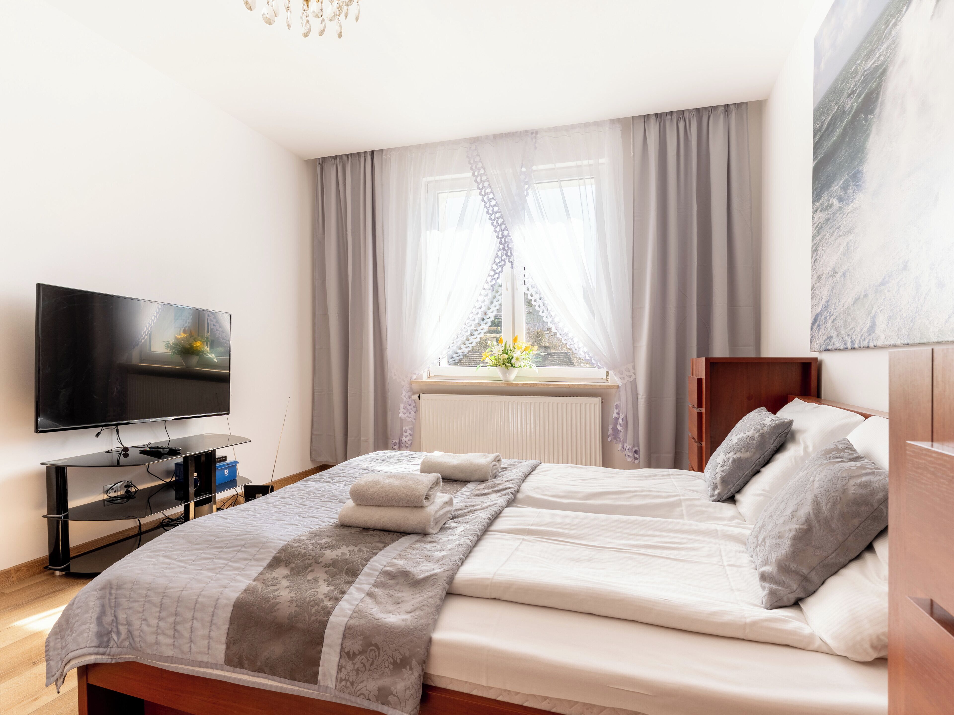 Une chambre à coucher avec un lit, une télévision, une fenêtre avec des rideaux et un radiateur.