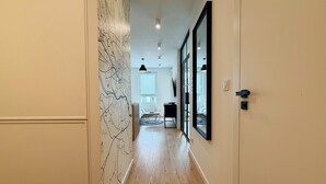 A hallway with a wooden floor, a map wall, and a large mirror. - Street Art Loft Apartment (Wrocław)