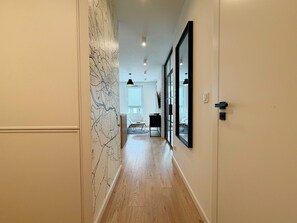 A hallway with a wooden floor, a map wall, and a large mirror. - Street Art Loft Apartment (Wrocław)