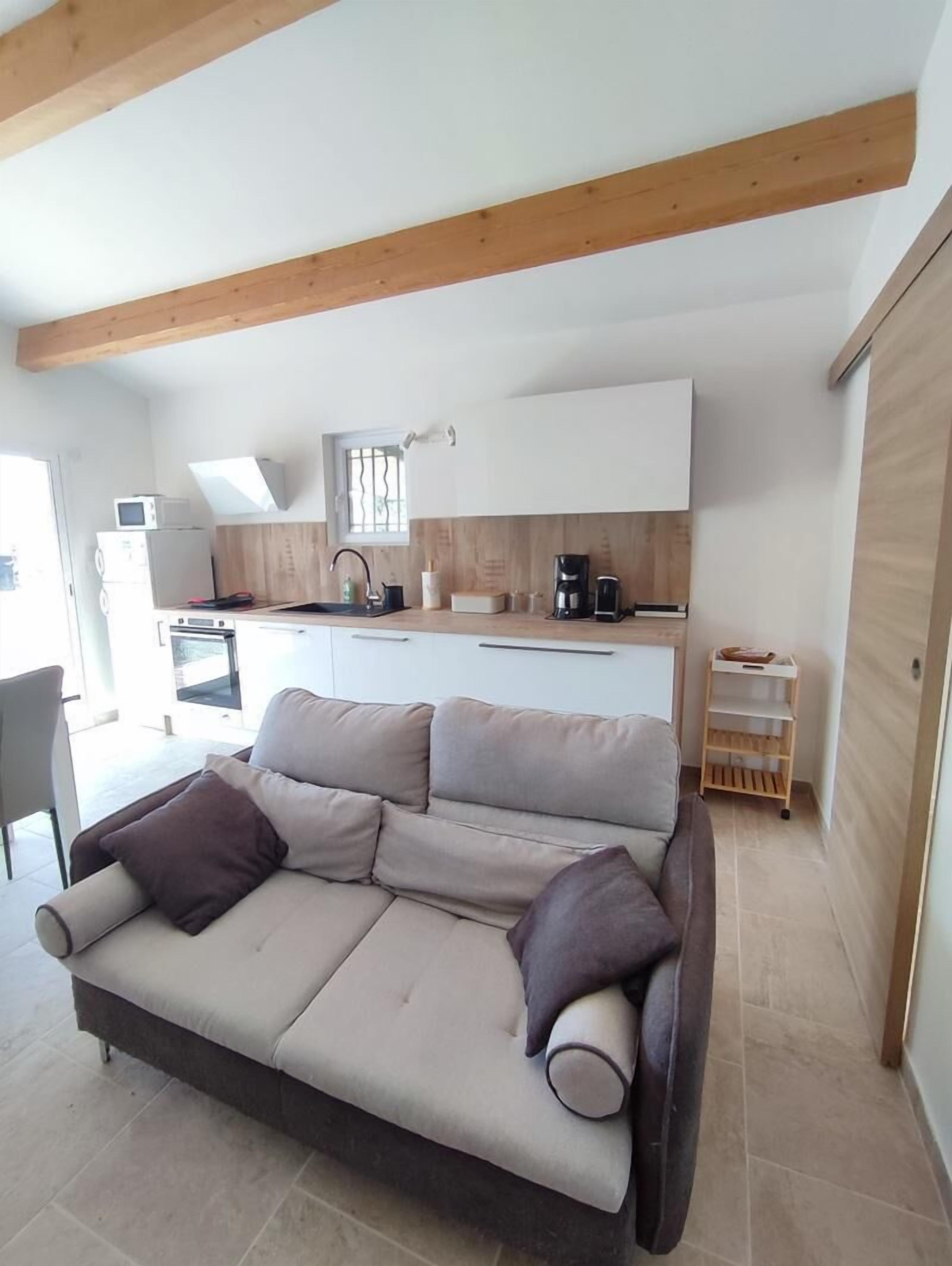 A modern kitchen with wooden beams, a sofa with cushions, and a small coffee station.