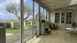 Una habitación amplia con ventanas grandes, una estantería y un espacio de descanso.