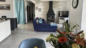 Una sala de estar con sofá, televisión, chimenea y comedor con mesa y sillas.