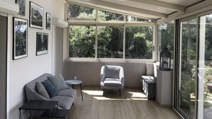 Una habitación iluminada por el sol con sofá, sillón, una mesita y un farol.
