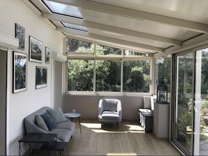 Ein sonnendurchfluteter Raum mit Sofa, Sessel, kleinem Tisch und einer Laterne.