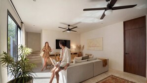 Una sala de estar moderna con sofá, ventiladores de techo, un ventanal grande y una planta en maceta.