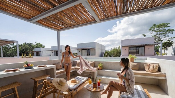 Un patio al aire libre con muebles de madera, una zona de comedor y vistas a edificios.