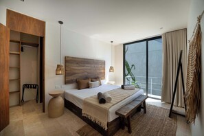 A bedroom with a large bed, wooden headboard, bedside lamps, a bench, and a view of the outdoors. - Seremonia Modern villa with 2 Private Pools (Tulum)