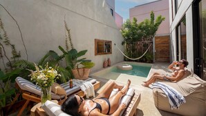 Área na beira da piscina com espreguiçadeiras, rede e uma pessoa relaxando.
