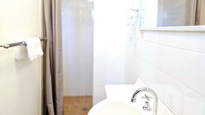 Een badkamer met een wit wastafel, een spiegel en een douchegedeelte.