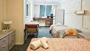 Hotelkamer met een bed, bureau, stoel, dressoir, magnetron en koelkast.