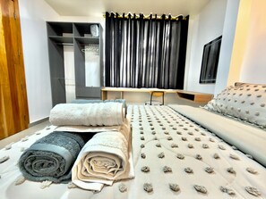 Een slaapkamer met een bed, een bureau en een kledingkast.