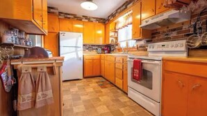 Une cuisine avec des meubles de rangement en bois, un réfrigérateur, un four et une cuisinière.