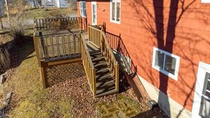 Un bâtiment rouge doté d’une terrasse en bois et d’un escalier menant à une porte.