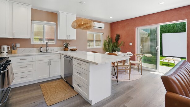 Une cuisine moderne avec des meubles blancs, un îlot central et un coin repas avec des chaises.