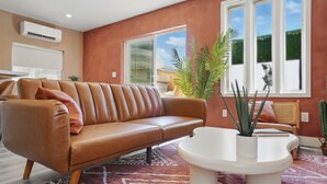 Un salon moderne avec un canapé en cuir, une table basse blanche et une grande fenêtre offrant une belle vue.