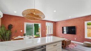 Une cuisine moderne dotée d’un grand îlot central, de meubles blancs et d’un luminaire suspendu.