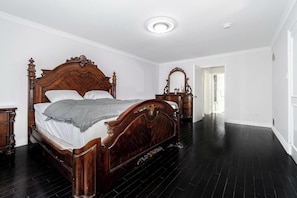 A bedroom with a large wooden bed, a dresser, and a mirror.