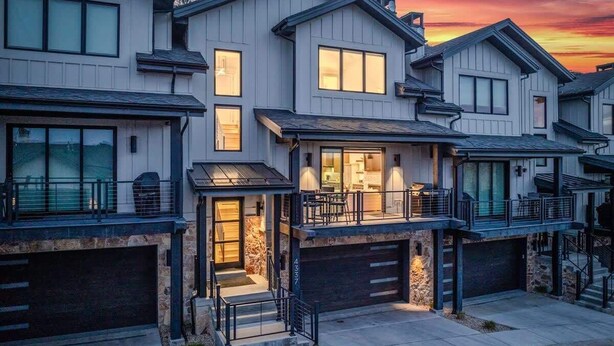 A modern residential building with multiple garage doors, a central entrance with steps, and a balcony with outdoor seating. - Abode at Canyons Retreat, hot tub, 4 king suites (Park City)