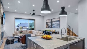 A modern kitchen with a central island, a dining area, and a living room with a sofa and coffee table. - Abode at Canyons Retreat, hot tub, 4 king suites (Park City)