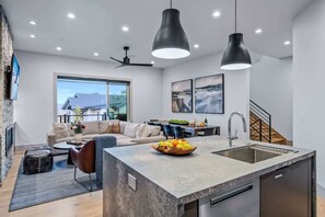 A modern kitchen with a central island, a dining area, and a living room with a sofa and coffee table. - Abode at Canyons Retreat, hot tub, 4 king suites (Park City)