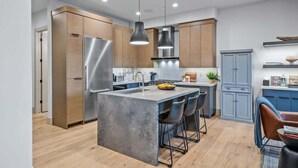 A modern kitchen with a central island, stainless steel appliances, and wooden cabinetry. - Abode at Canyons Retreat, hot tub, 4 king suites (Park City)