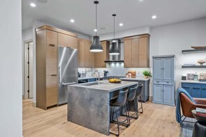 A modern kitchen with a central island, stainless steel appliances, and wooden cabinetry. - Abode at Canyons Retreat, hot tub, 4 king suites (Park City)