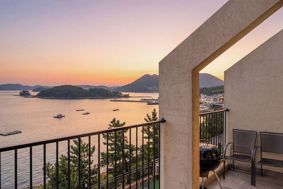 A balcony with a view of a body of water, boats, and distant landforms.