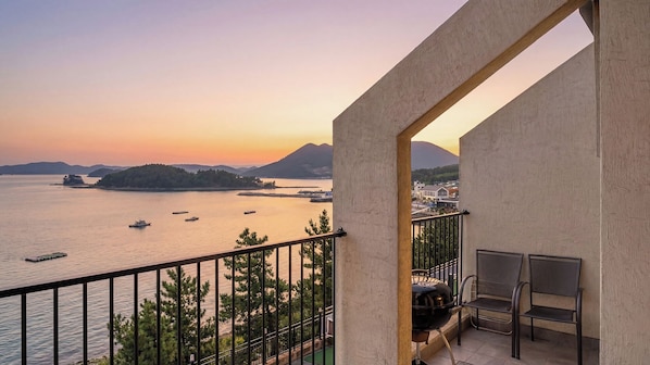A balcony with a view of a body of water, boats, and distant landforms.