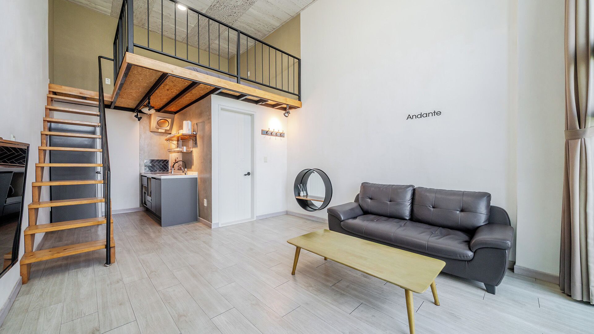 A modern living space with a loft bedroom, a dining area, and a sofa.