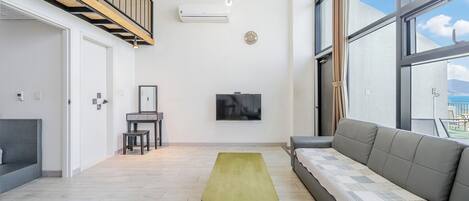 A modern living room with a sofa, a small table, a TV, and a staircase.