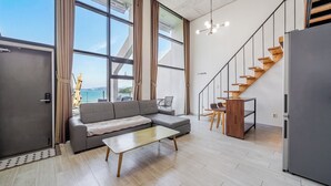 A modern living space with a sofa, coffee table, and a staircase. - Yeosu Andante Spa Pension (Yeosu)
