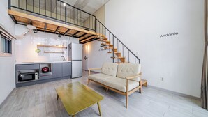 A modern apartment with a kitchen, a sofa, a dining table, and a staircase. - Yeosu Andante Spa Pension (Yeosu)