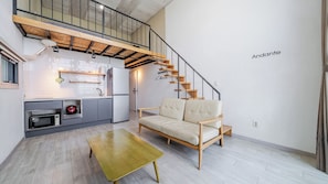 A modern apartment with a kitchen, a sofa, a dining table, and a staircase.