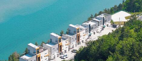 A coastal hotel with modern architecture, a swimming pool, and a view of the sea.
