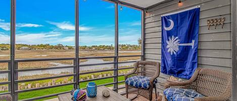 A balcony with wicker chairs, a table, and a flag.