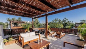 An outdoor patio with wooden furniture, a hammock, and a pergola structure. - Villa Selva | 4BR Villa w/ Private Pool & Rooftop (Tulum)