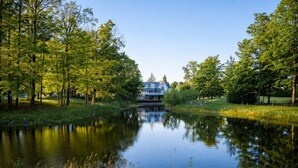Un entorno tranquilo junto al lago con una casa, árboles y una superficie acuática serena.