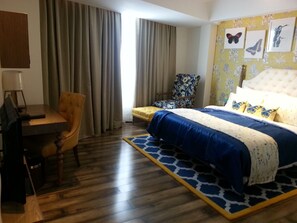 Ein Hotelzimmer mit Bett, Schreibtisch, Stuhl und einem fenster mit Vorhängen.