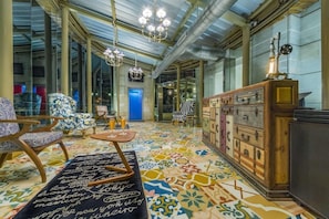 A spacious room with a patterned floor, a wooden cabinet, and a chandelier.