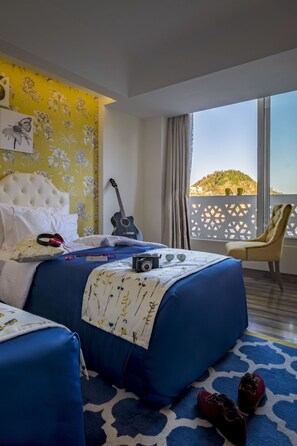 A hotel room with a bed, a guitar, a camera, and a pair of shoes on the floor. - Mosaic Mussoorie (Dehradun)