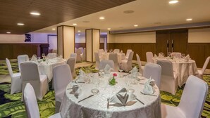 A banquet hall with round tables set for dining, white chairs, and a wooden ceiling. - Mosaic Mussoorie (Dehradun)
